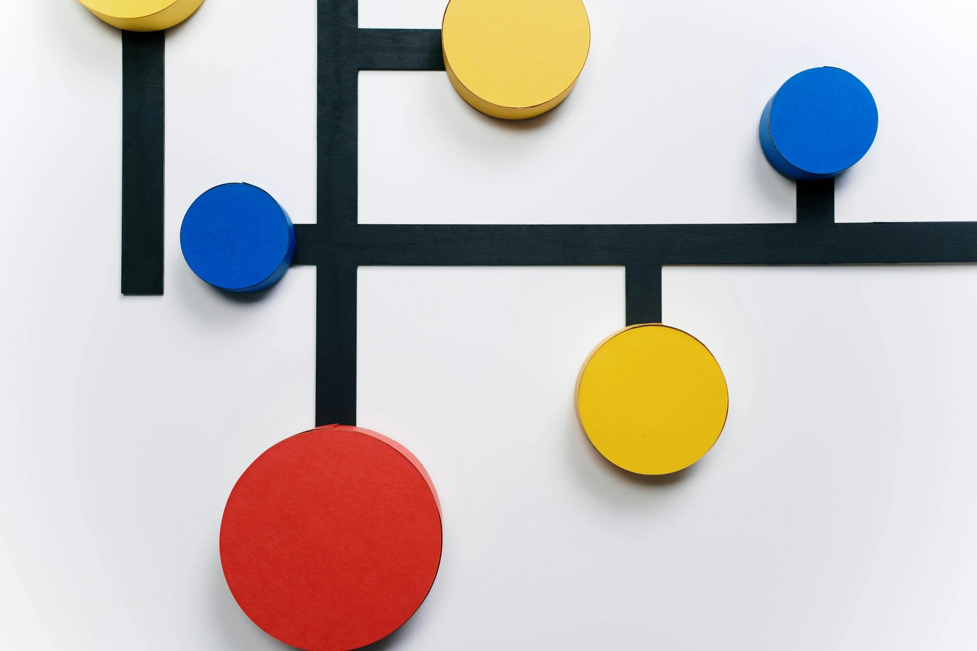 Abstract wall art with colorful circles on dark intersecting lines against a white background