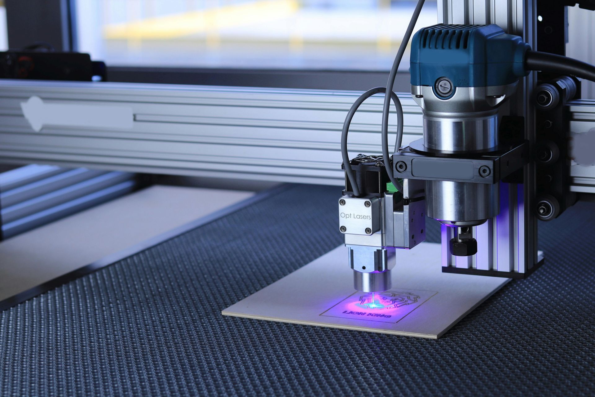 Laser cutter engraving cardboard. Machine with a blue laser, operating on a table.