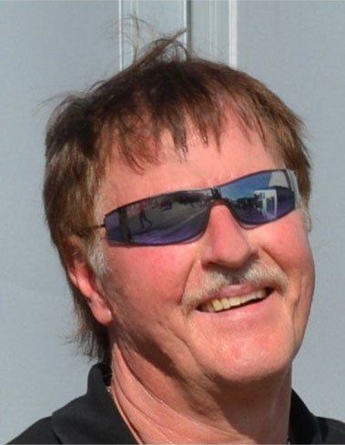 Lächelnder Mann mit dunkler Sonnenbrille vor hellgrauem Hintergrund