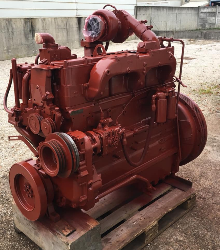 Un motore diesel industriale, verniciato di rosso di recente e dotato di turbocompressore, appoggiato su un pallet di legno all'aperto.