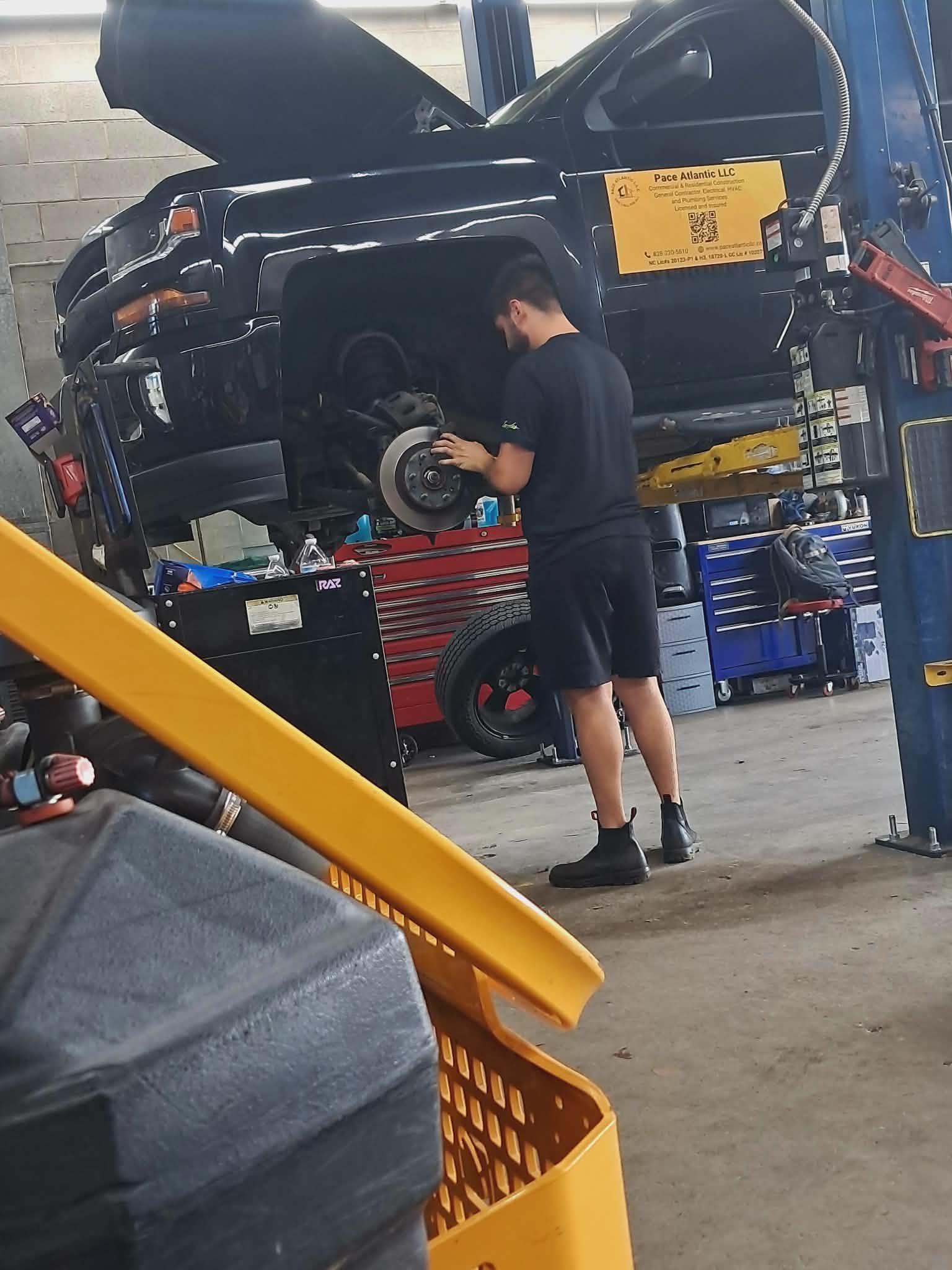 A gloved hand removes a plug from a vehicle's undercarriage to drain oil.