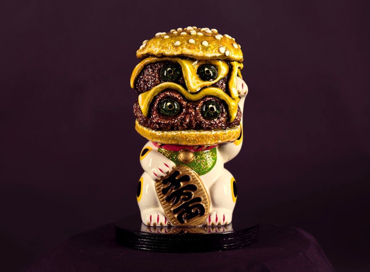 Art by Rich M Stevens. Small decorative figurine with a colorful abstract mask, standing against a dark purple background.