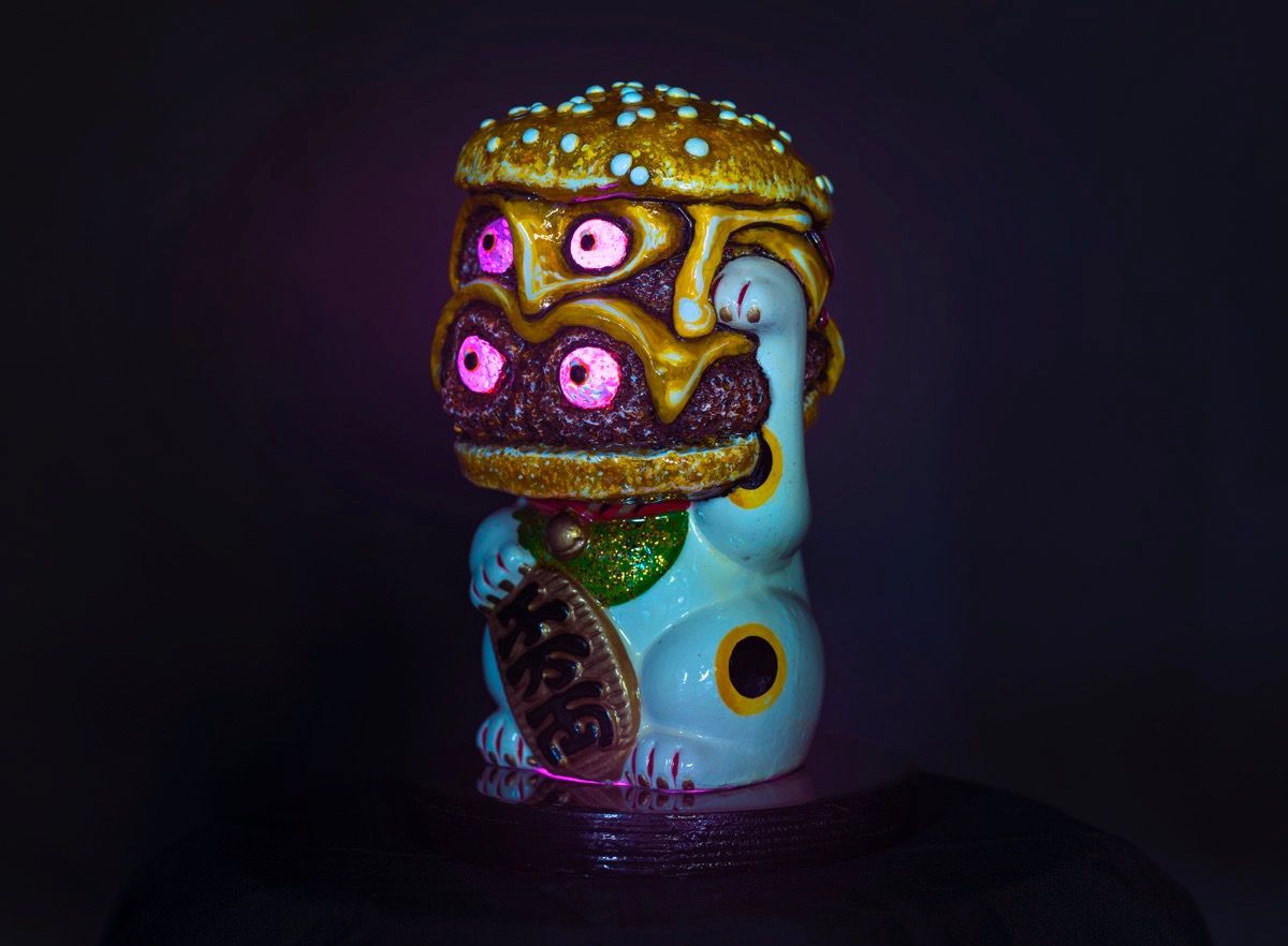 Art by Rich M Stevens. Colorful stylized creature sculpture with glowing pink eyes on a dark background