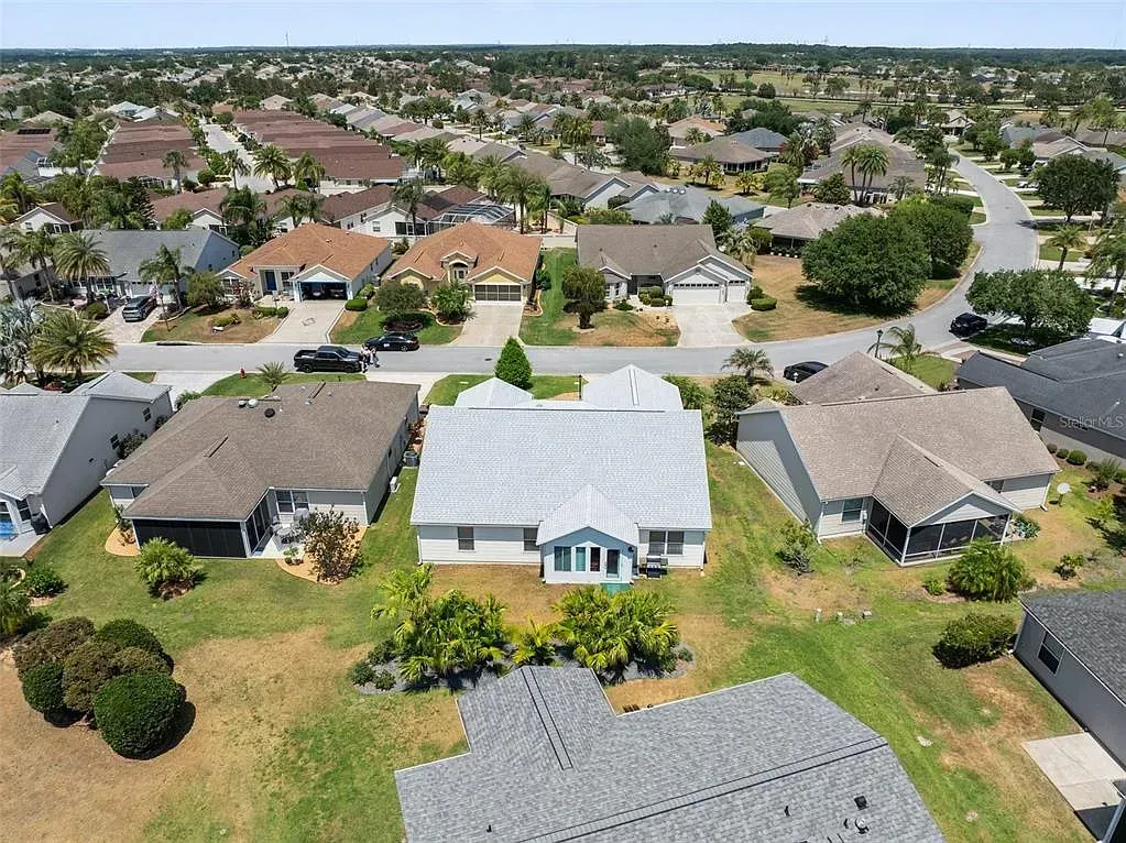 Aerial view of a suburban neighborhood with rows of single-story houses and tree-lined streets.