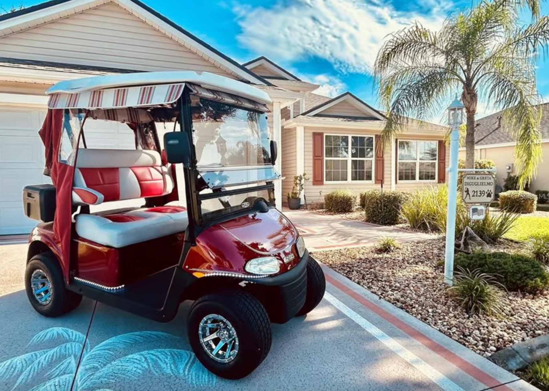 A red golf cart is parked in front of a house.
