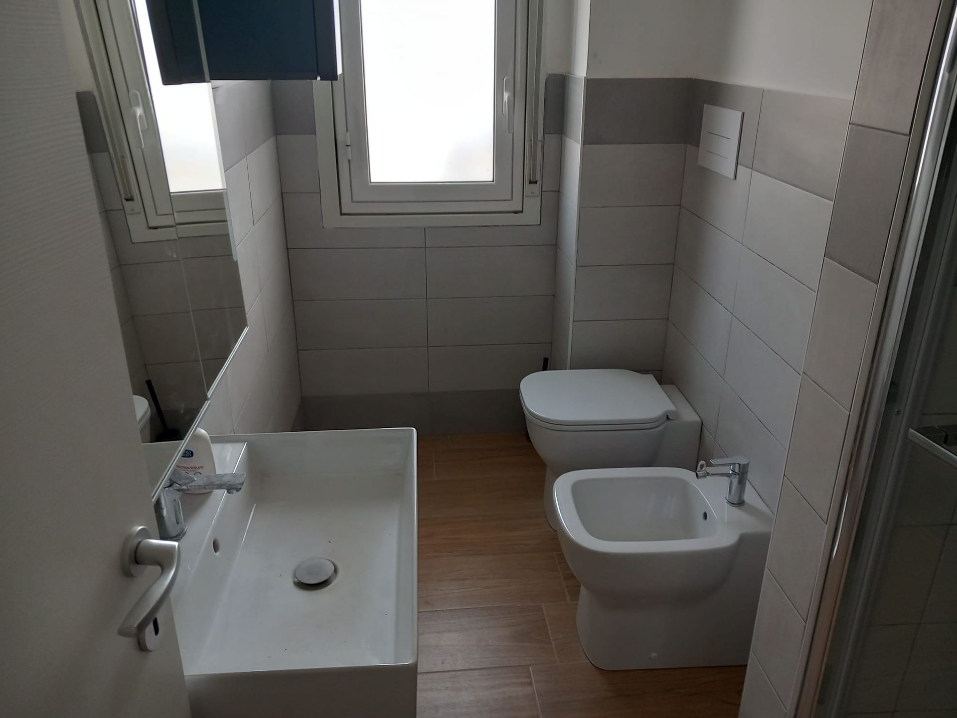 Ampio soggiorno con divano componibile beige, tavolino da caffè scuro, tende dorate e pavimento in legno.