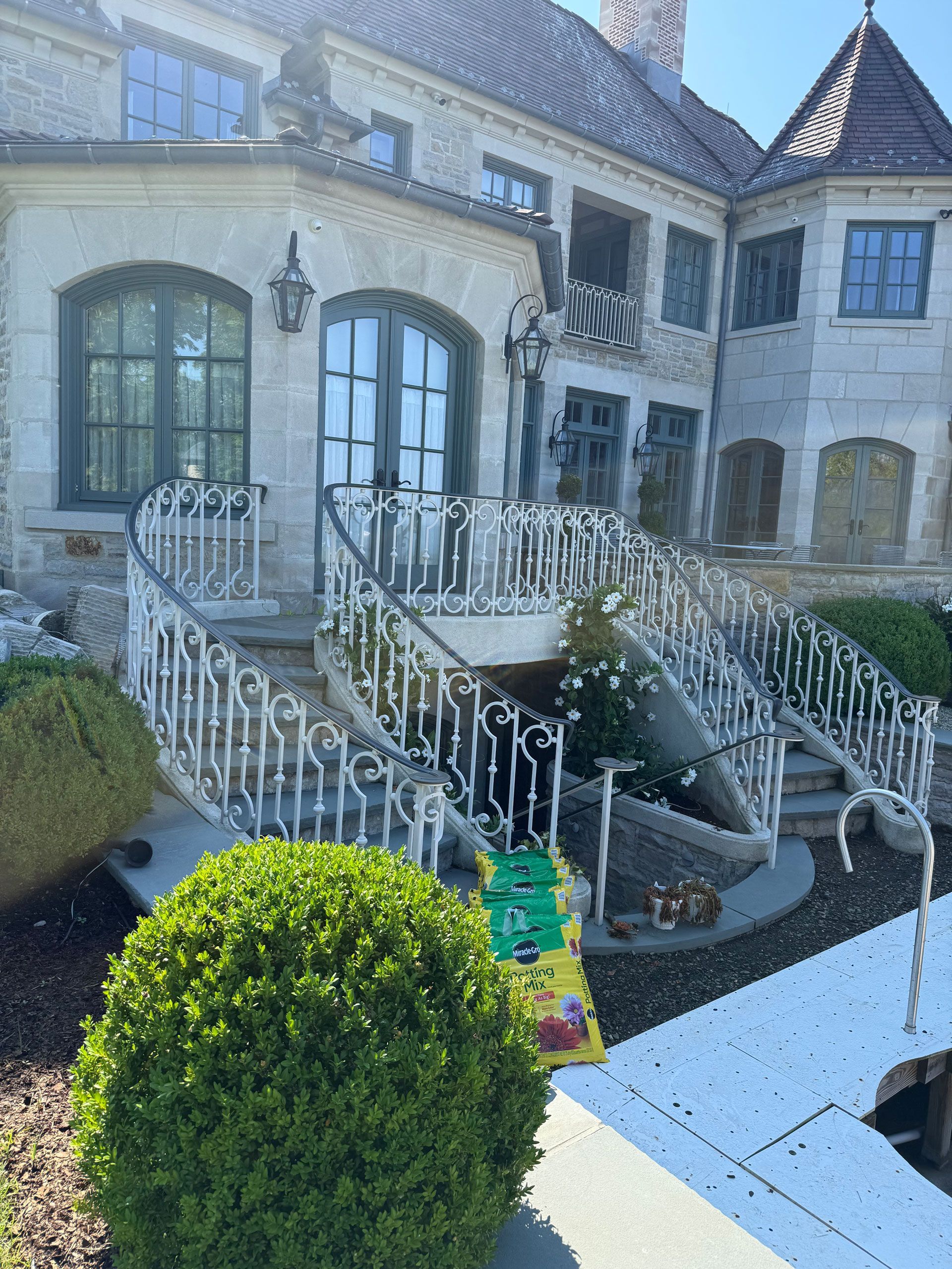 Decorated house exterior with white railings, stone facade, and a small sign near the entrance