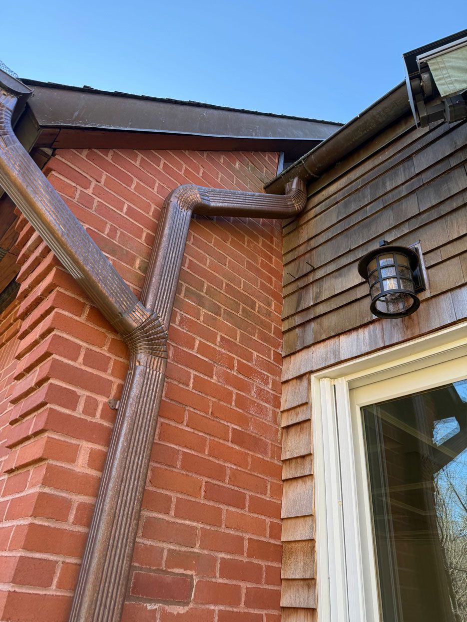 Brick house exterior with brown guttering and a window light fixture