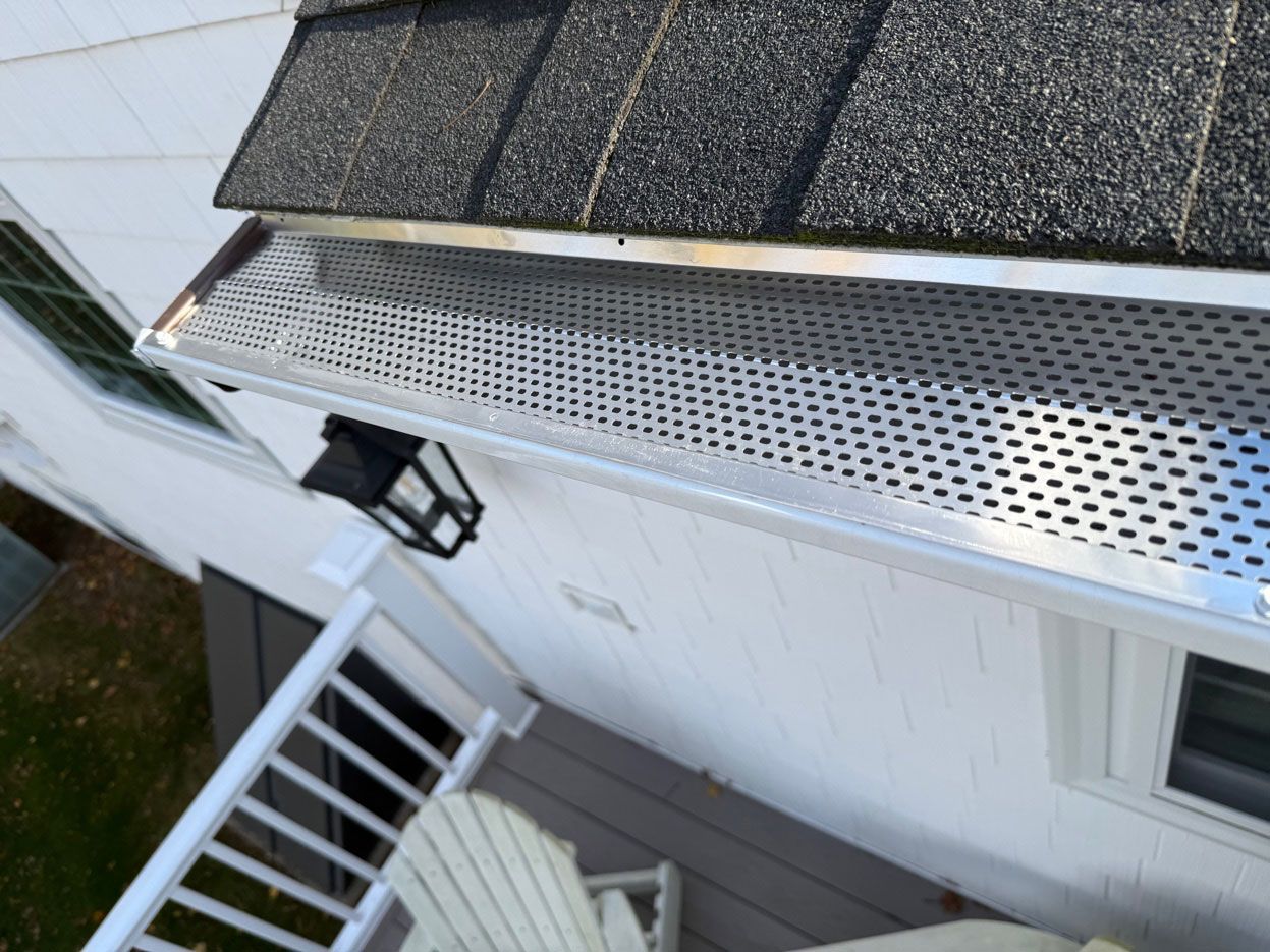 Overhead view of a house roof, gutter, and porch with white siding and stairs