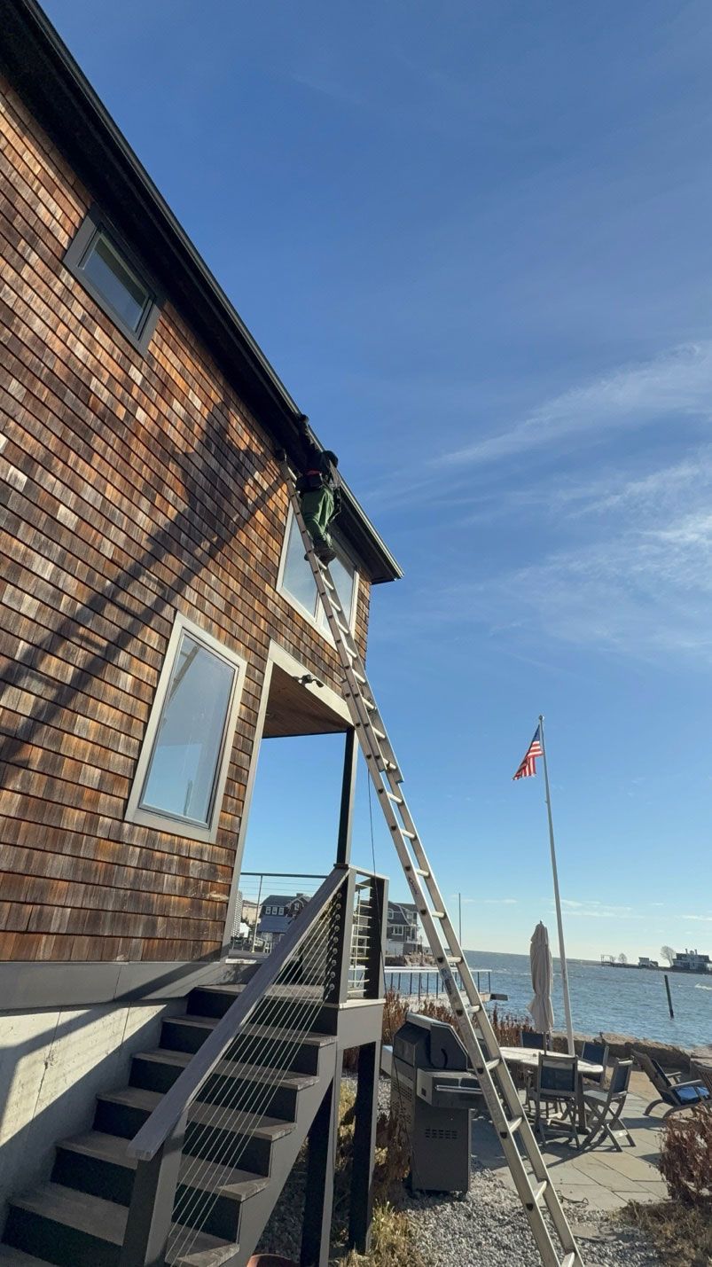 Sunlit waterfront house with stairs and American flag against a clear blue sky