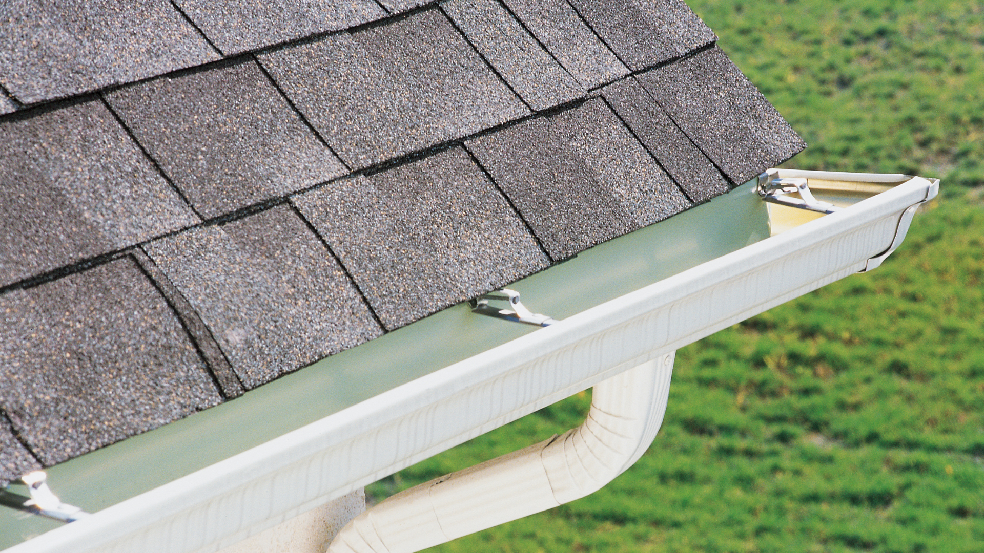 Hand lifting a shingle to reveal roof flashing and gutter repair area