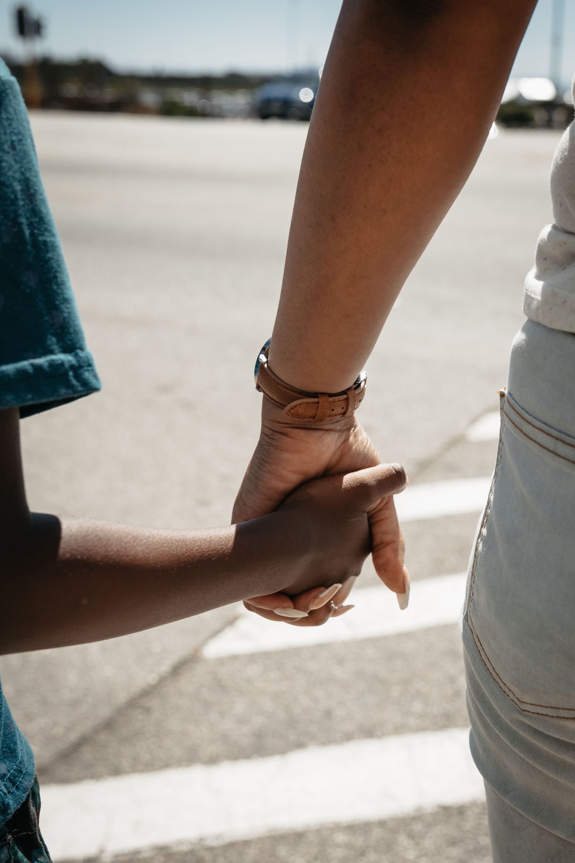 Two people holding hands outdoors on a sunlit street