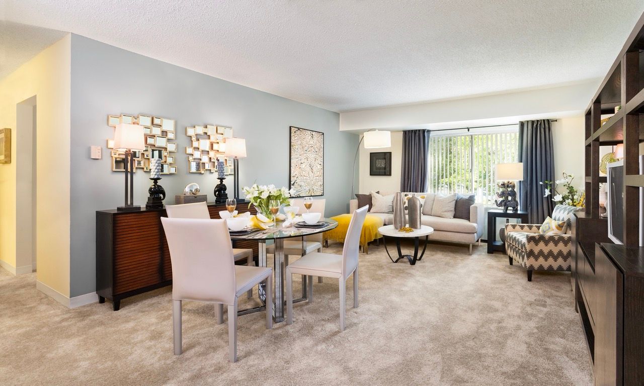 Open-concept living and dining area in a modern apartment with neutral furnishings.