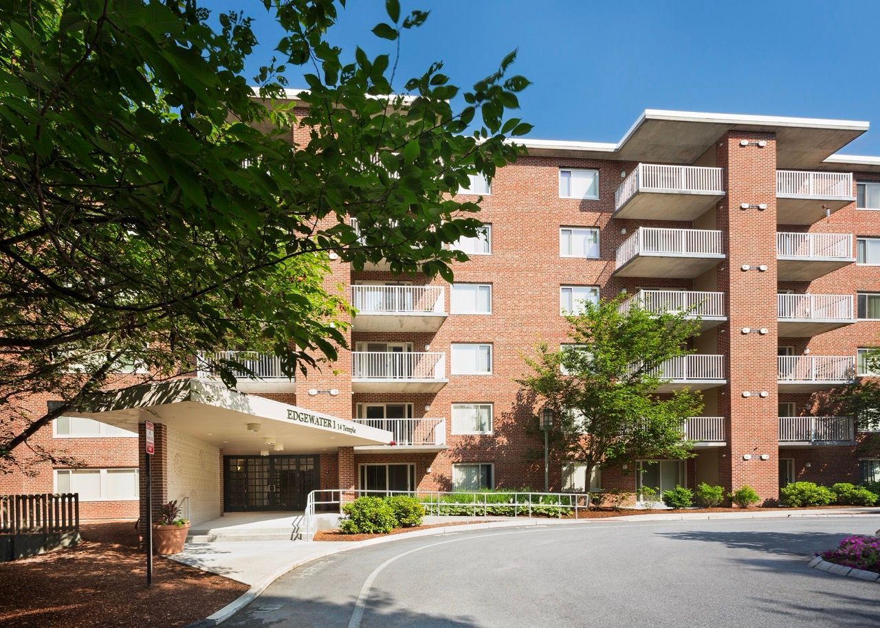 Brick apartment building exterior with balconies and a curved driveway.
