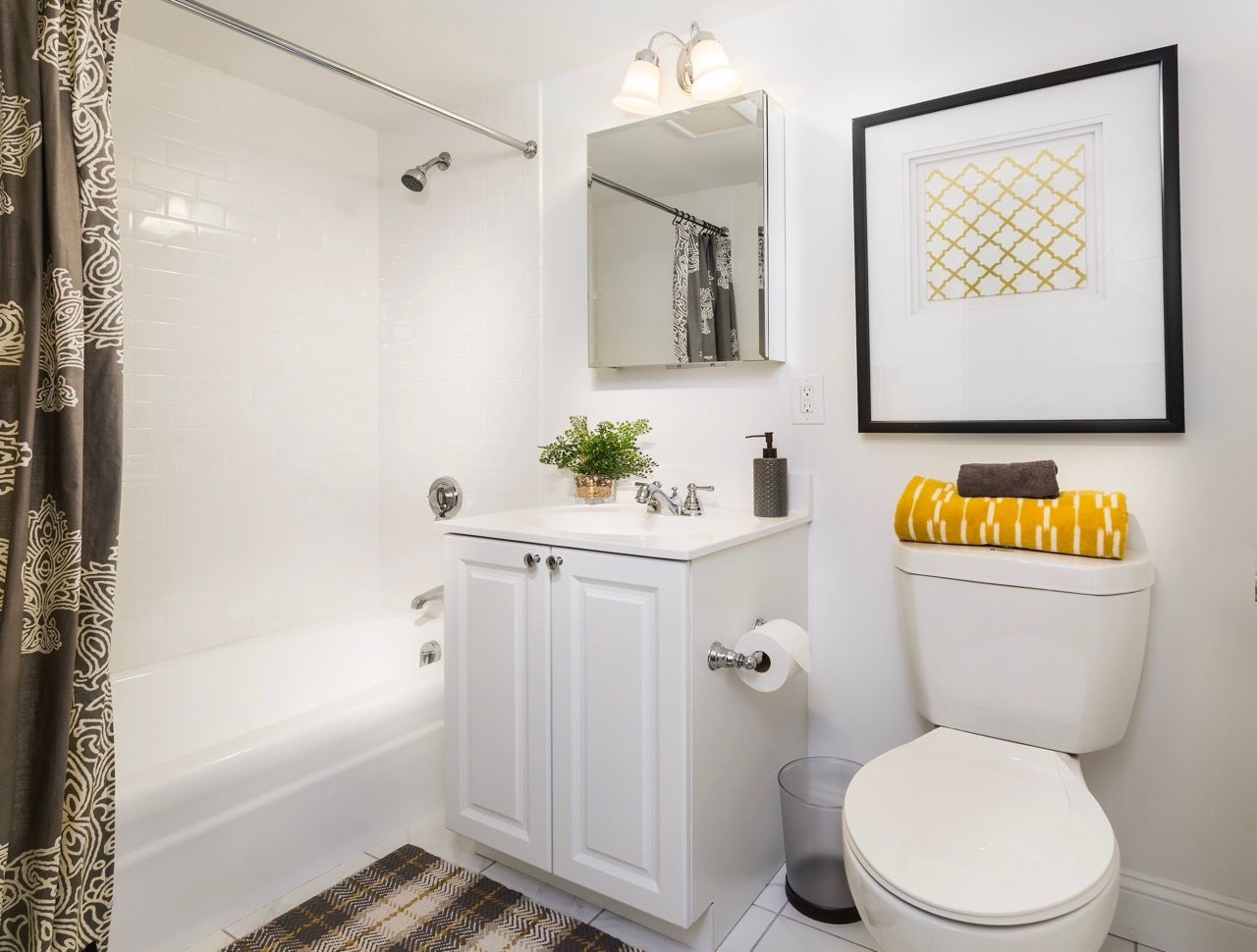 Bright white bathroom with a vanity, mirror, toilet, and tiled shower.