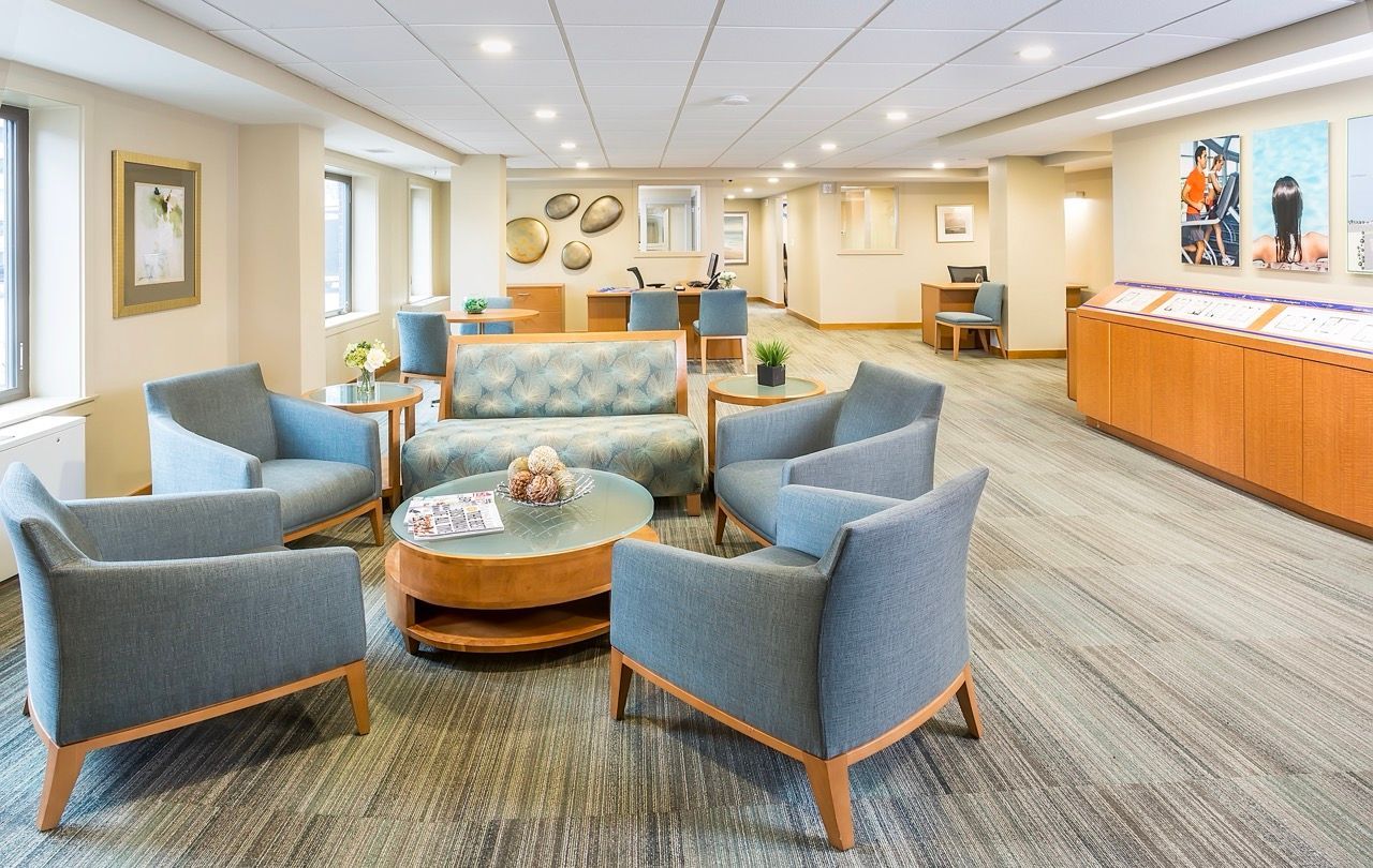 Bright apartment community lounge with blue upholstered chairs around a round coffee table.