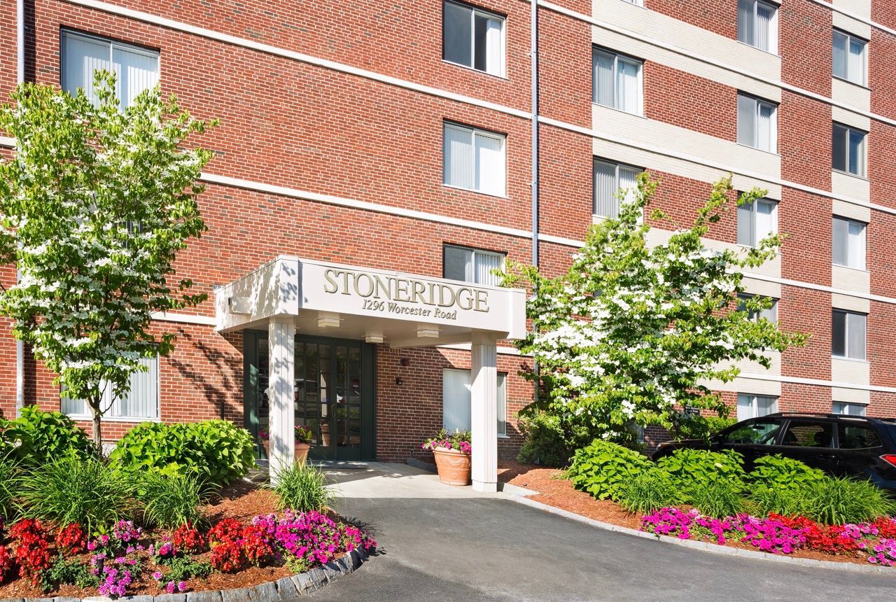 Exterior of a brick apartment building with a landscaped entrance and a StoneRidge sign.