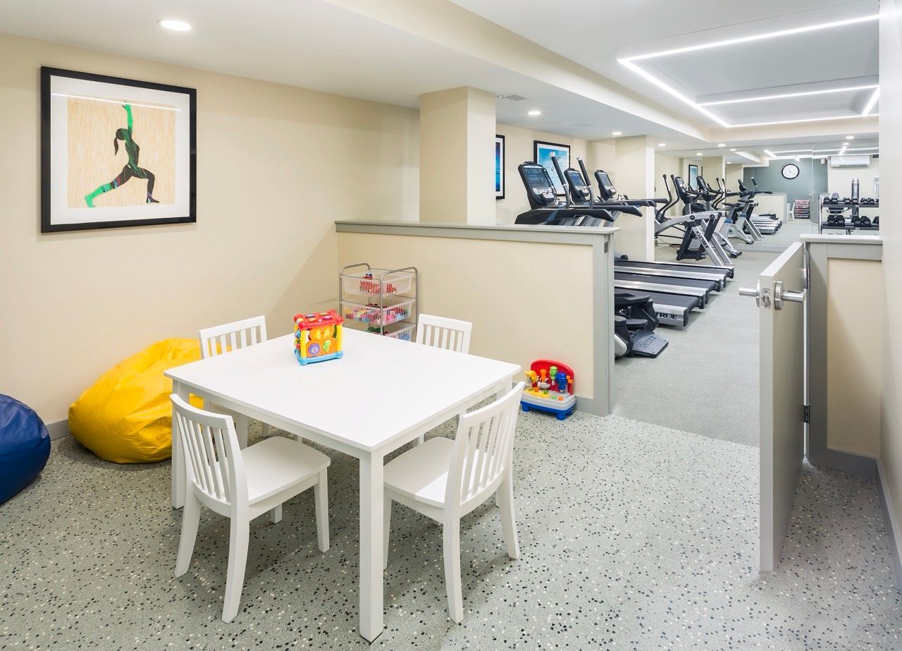 Interior community gym with treadmills and a small children's play table.