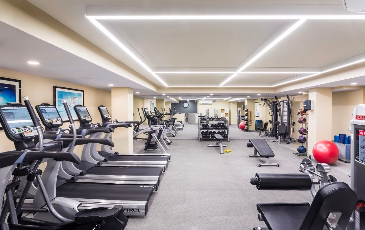 Well-lit gym with treadmills, weights, and fitness equipment.
