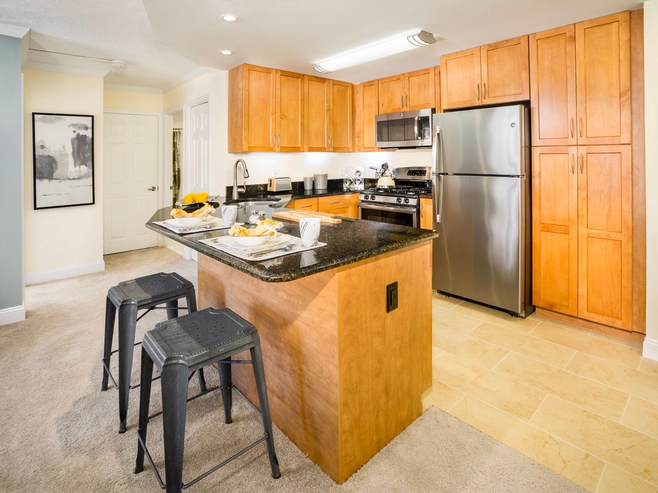Open-concept kitchen with granite island, stainless steel appliances, and maple cabinets.