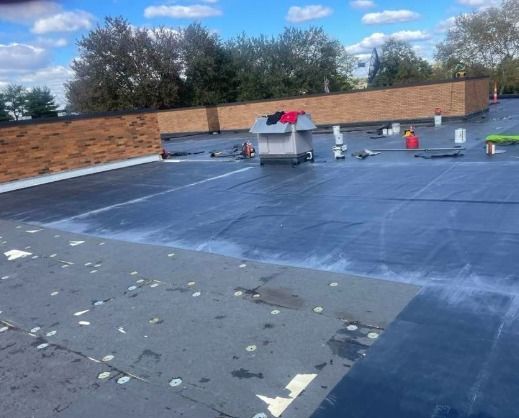 Flat commercial roof with equipment, under a blue sky.
