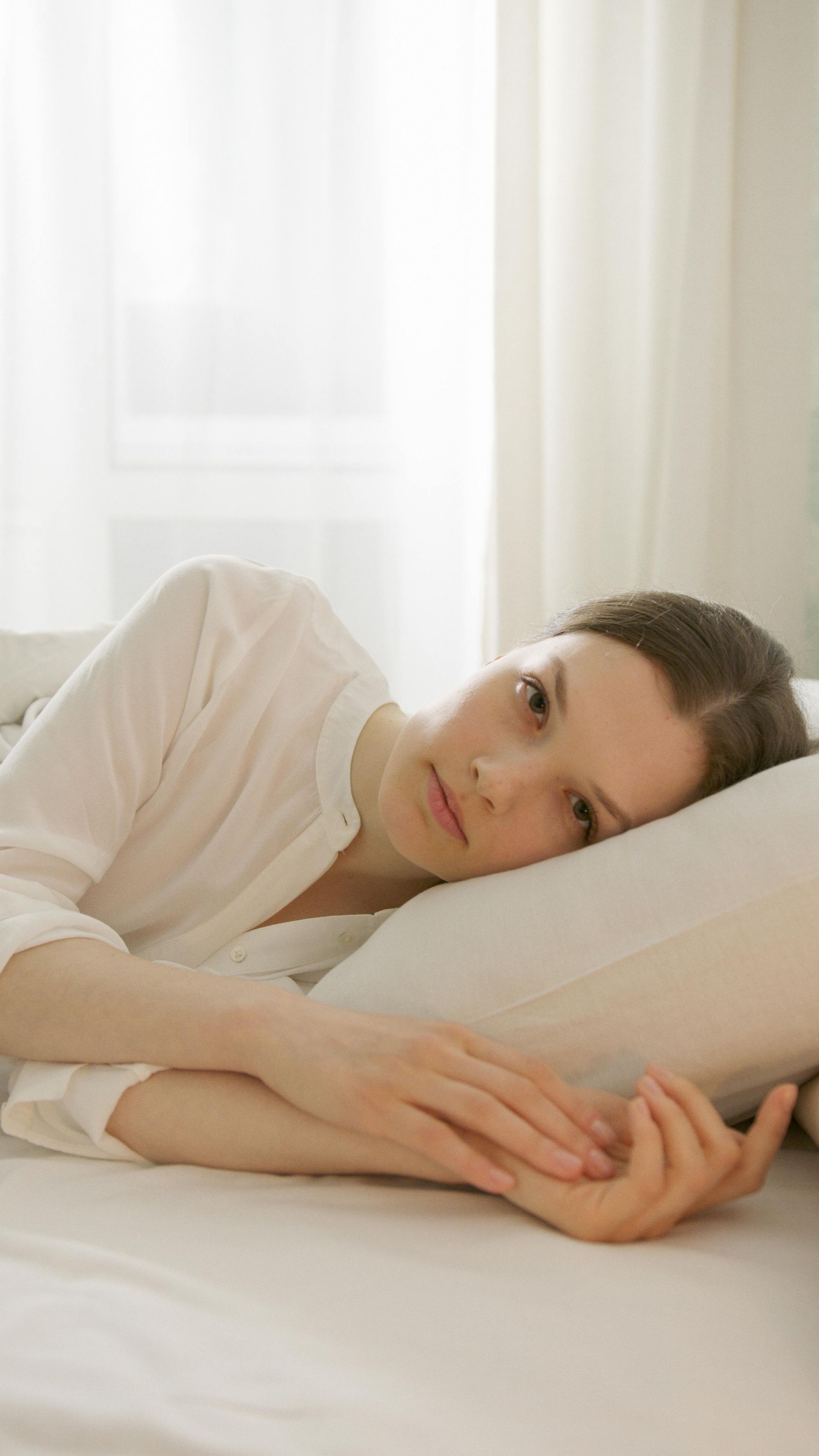 Erschöpfte Frau sitzt müde auf einer Couch und findet keine Ruhe.