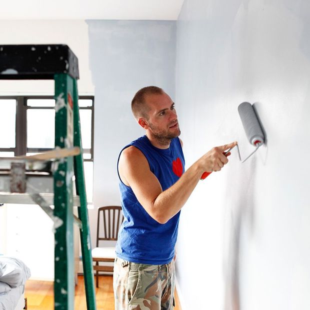 Man painting a wall blue with a paint roller; interior setting, green ladder. Man painting a wall blue with a paint roller; interior setting, green ladder.
