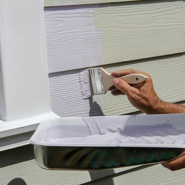 Hand painting siding with a brush, showing the color change from tan to lavender. Hand painting siding with a brush, showing the color change from tan to lavender.