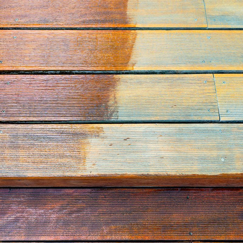 Wooden deck planks partially cleaned; shows contrast between stained and weathered areas. Wooden deck planks partially cleaned; shows contrast between stained and weathered areas.