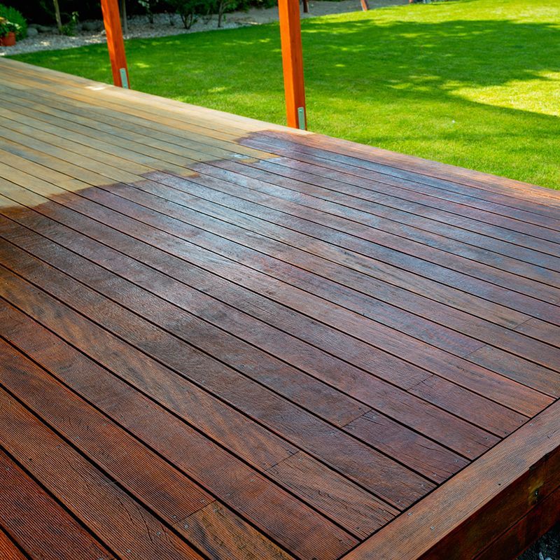 Wooden deck with dark stain, in a sunny yard. Wooden deck with dark stain, in a sunny yard.