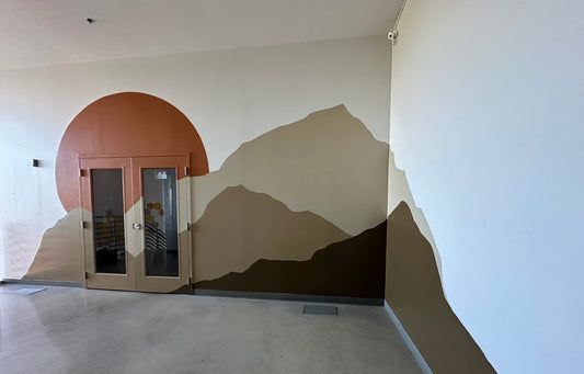 Interior wall mural with a sun and mountain range in shades of brown and tan. Double doors.