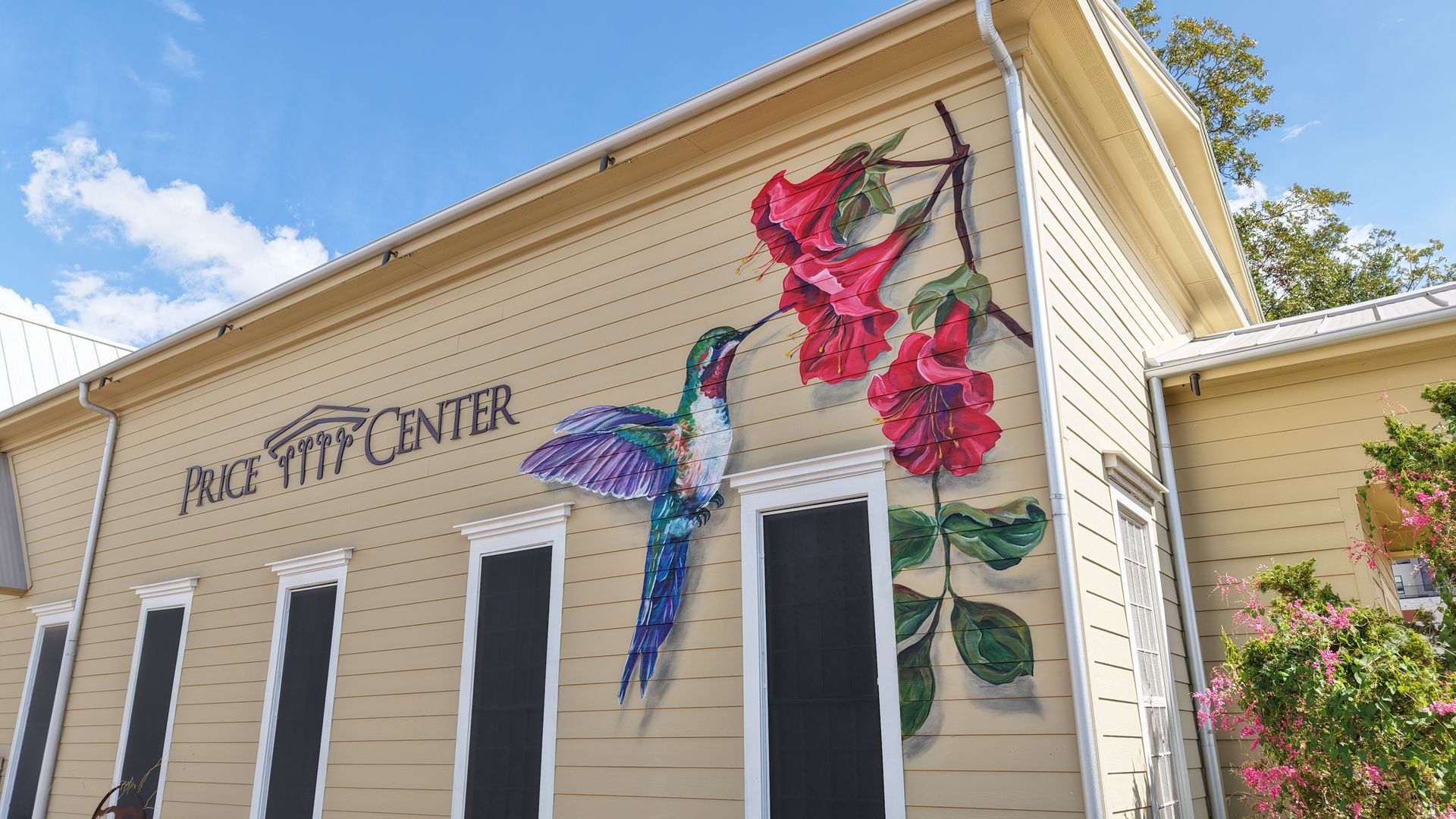 Flower mural on beige building reading “Visitor Center,” with pink, blue, and green blossoms on the wall