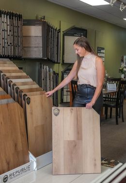 A woman is holding a piece of wood in a store.