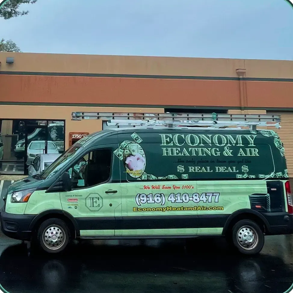 A green van for economy heating and air is parked in front of a building
