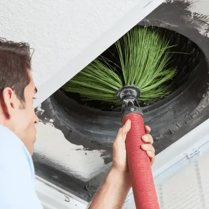 A man is cleaning an air vent with a brush