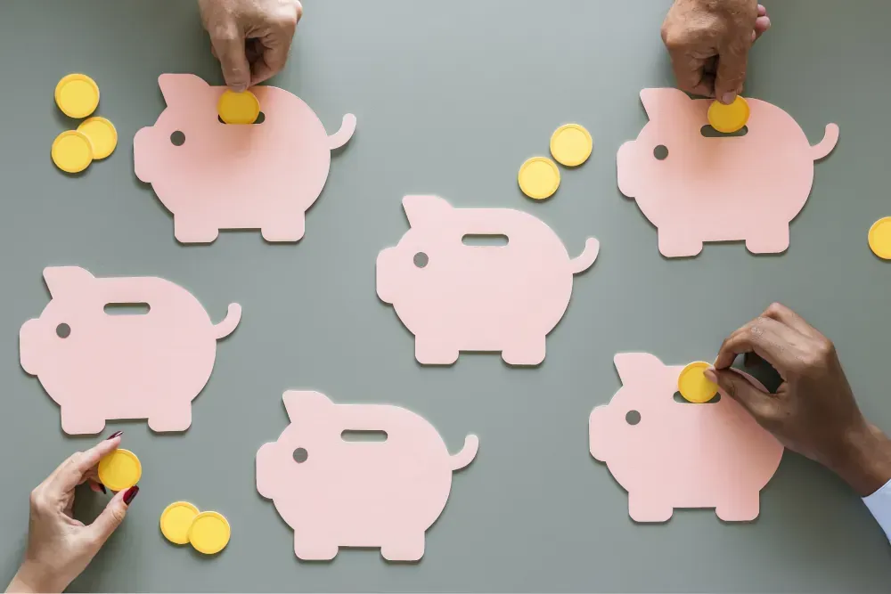 A group of people are putting coins into pink piggy banks.