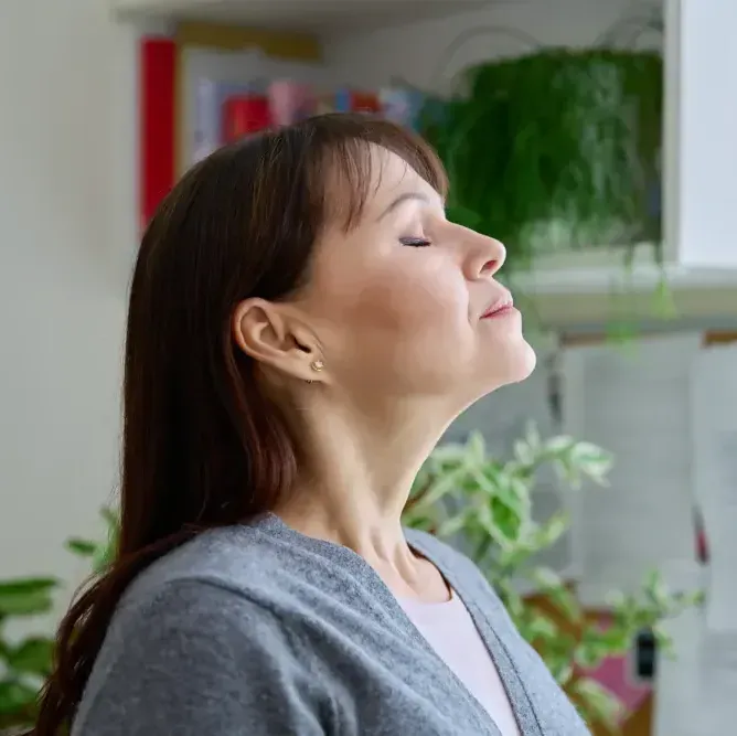 A woman is standing in a room with her eyes closed.