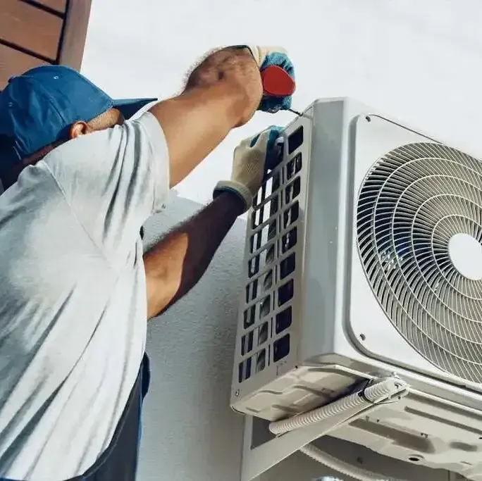A man is fixing an air conditioner with a screwdriver