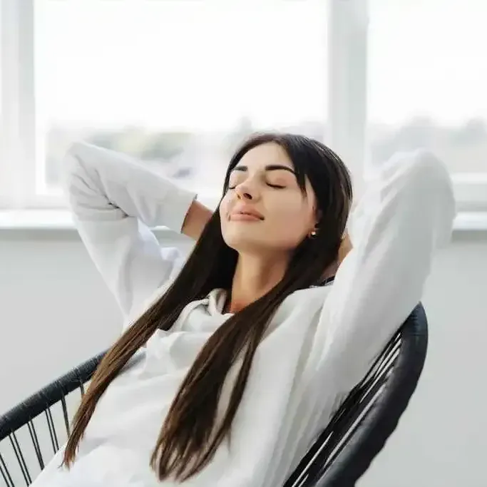 A woman is sitting in a chair with her eyes closed.