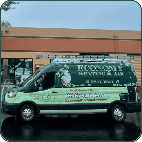 A green economy heating and air van is parked in front of a building