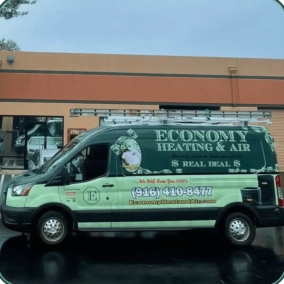 A green economy heating and air van is parked in front of a building