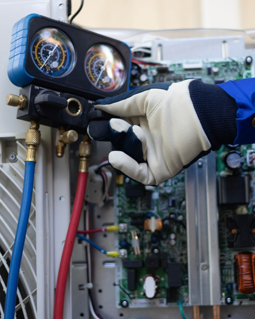 A man is fixing an air conditioner with a screwdriver.