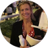 A woman is smiling while holding a cup of coffee and a piece of paper.