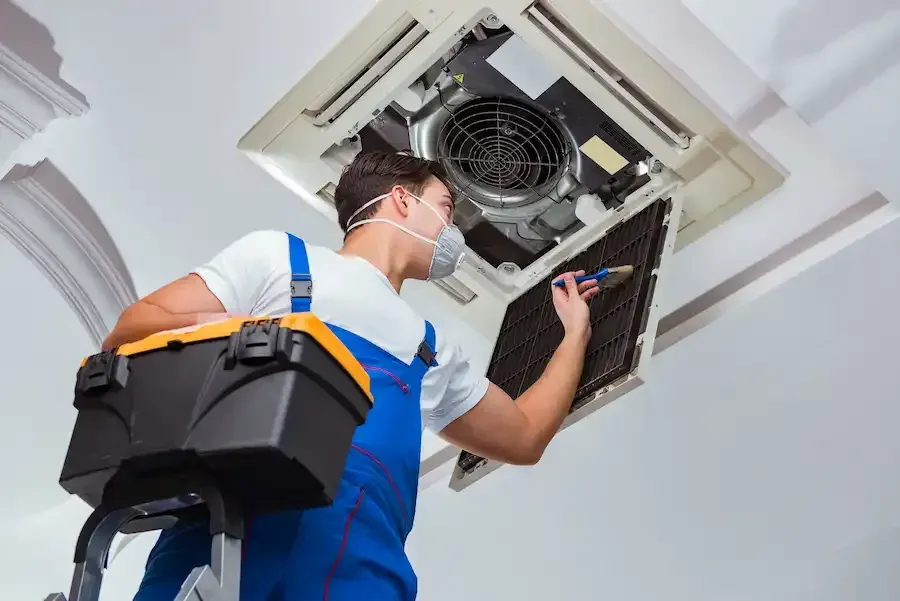 A man wearing a mask is working on an air conditioner.