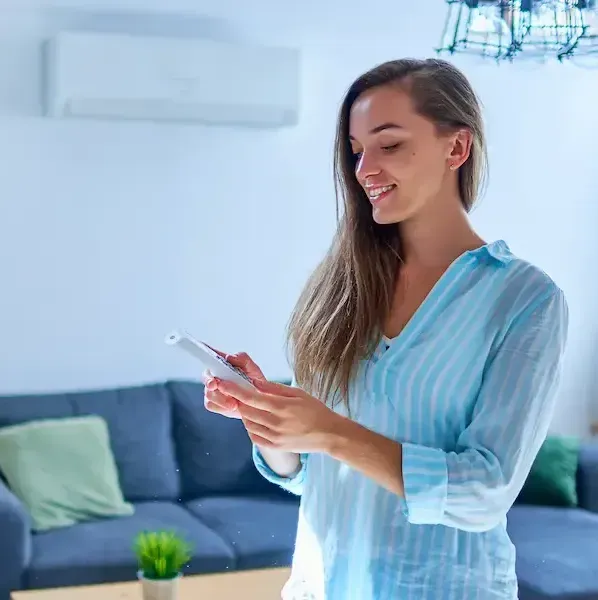 A woman is standing in a living room looking at a tablet.
