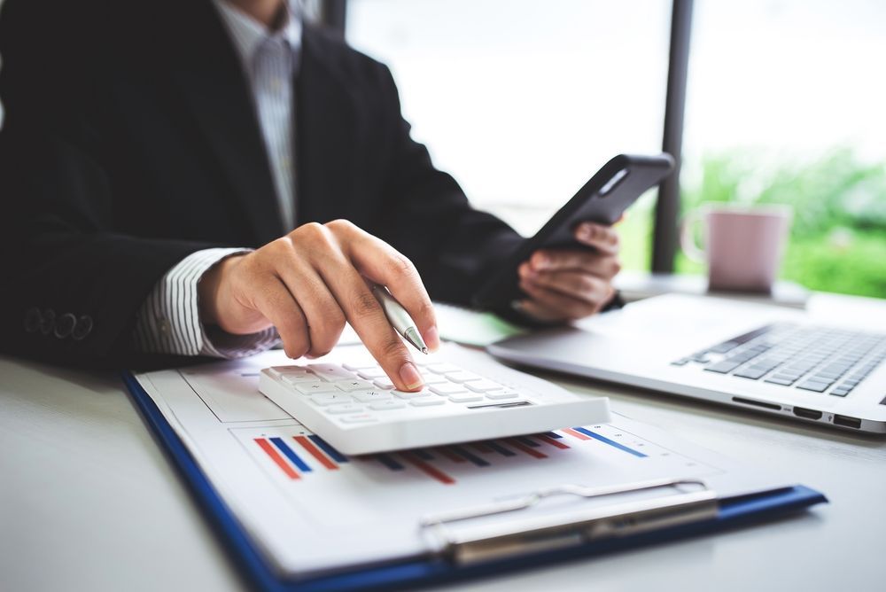 Person in Business Suit Using Calculator, Phone — AJA Bookkeeping Services In Cairns, QLD