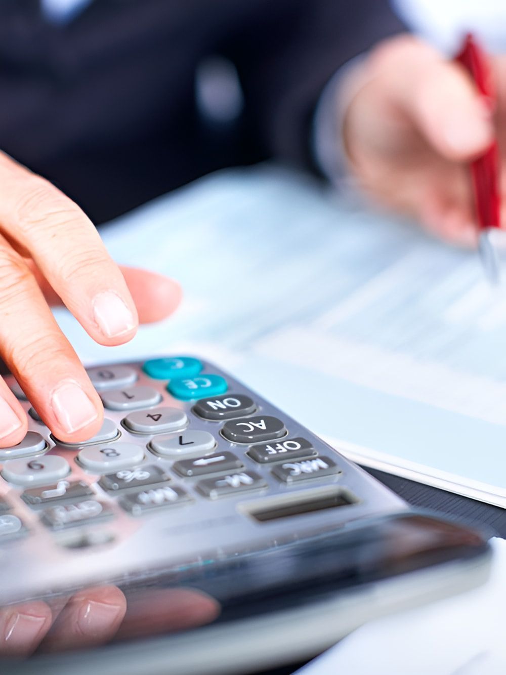 Person's Hands Using a Calculator and Writing With a Pen on a Document — AJA Bookkeeping Services In Normanton, QLD