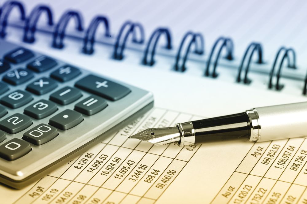 Calculator, Pen, and Notebook on Top of Financial Spreadsheet — AJA Bookkeeping Services In Weipa, QLD