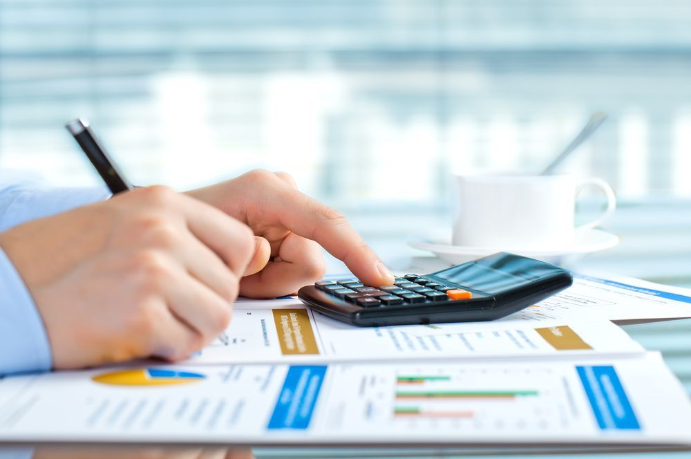 A Person's Hands Calculating With a Calculator and Writing on Papers — AJA Bookkeeping Services In Cooktown, QLD