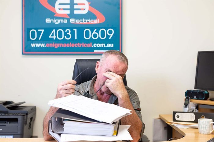A Man Rubbing His Eyes While Trying To Do Book Work — AJA Bookkeeping Services In Cairns, QLD